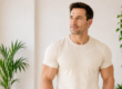 Lean, muscular man in his 40s by a sunlit window, representing muscle maintenance and general well-being in adult men