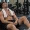 Man resting against a gym mirror after training, looking fatigued